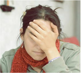 photo of woman with slightly lowered head covering her upper face with her hand