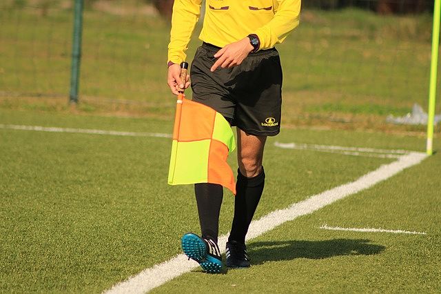 soccer lineman holding a yellow and orange check flag