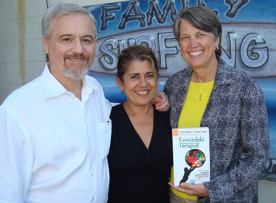 photo of christine a padesky phd holding the turkish translation of the first edition of mind over mood. In the middle is dr emel stroup the primary translator of the first edition. on the left is dennis greenberger phd