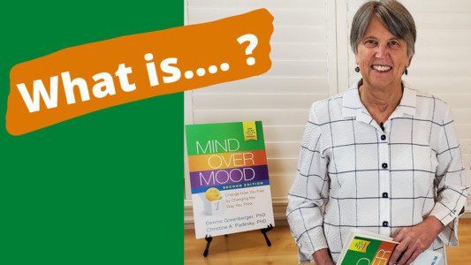 photo of dr christine padesky holding a mind over mood second edition and asking what is