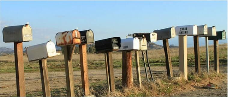row of vintage metal mail boxes on wooden posts in a rural midwestern plains setting