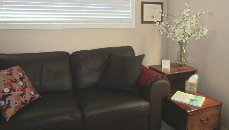 photo of therapist couch with end table and copy of mind over mood first edition book